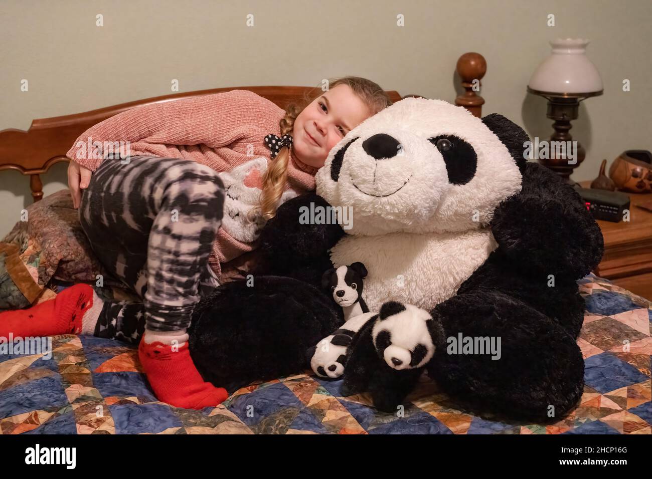 Issaquah, Washington, États-Unis.fille de 5 ans embrassant un grand et bébé des ours de panda farcis sur un lit.(M.) Banque D'Images