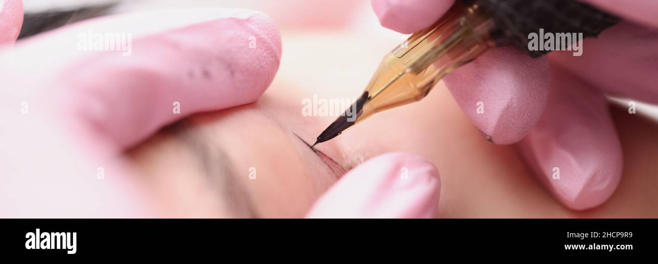 L'artiste maître de maquillage fait un maquillage permanent pour les paupières d'un client Banque D'Images
