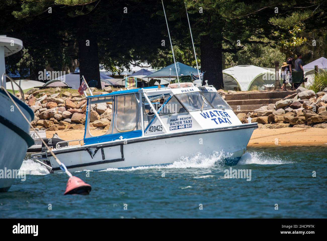 Le bateau-taxi quitte le quai au terrain de camping du bassin à Pittwater, Sydney, Australie Banque D'Images