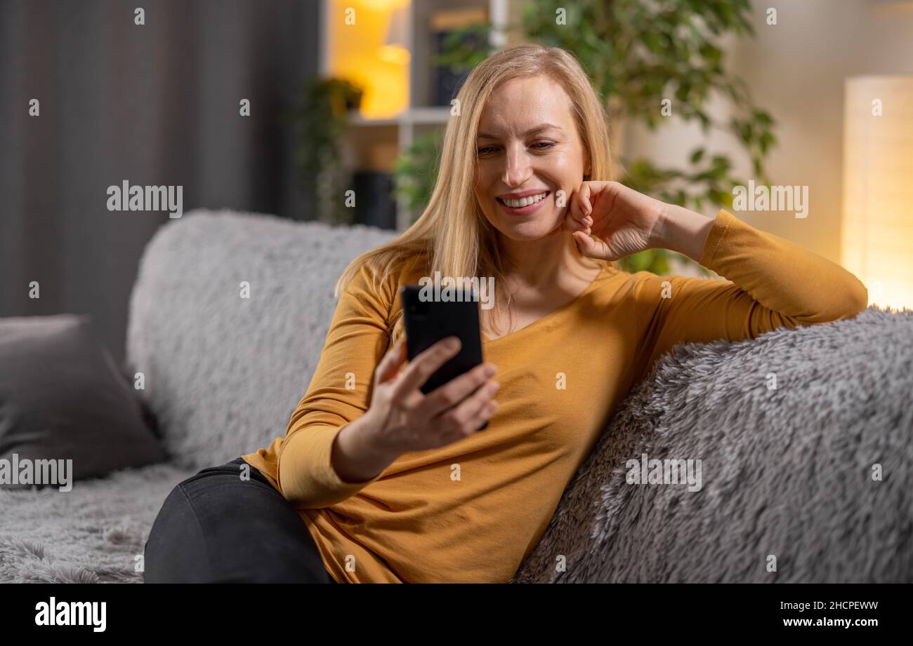 Femme utilisant le mobile sur le canapé Banque D'Images