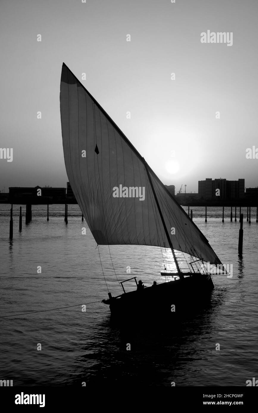 Image monochrome d'un dhow en lateen dans les eaux du golfe Persique, au coucher du soleil au Louvre, île de Saadiyat, Abu Dhabi, Émirats arabes Unis Banque D'Images
