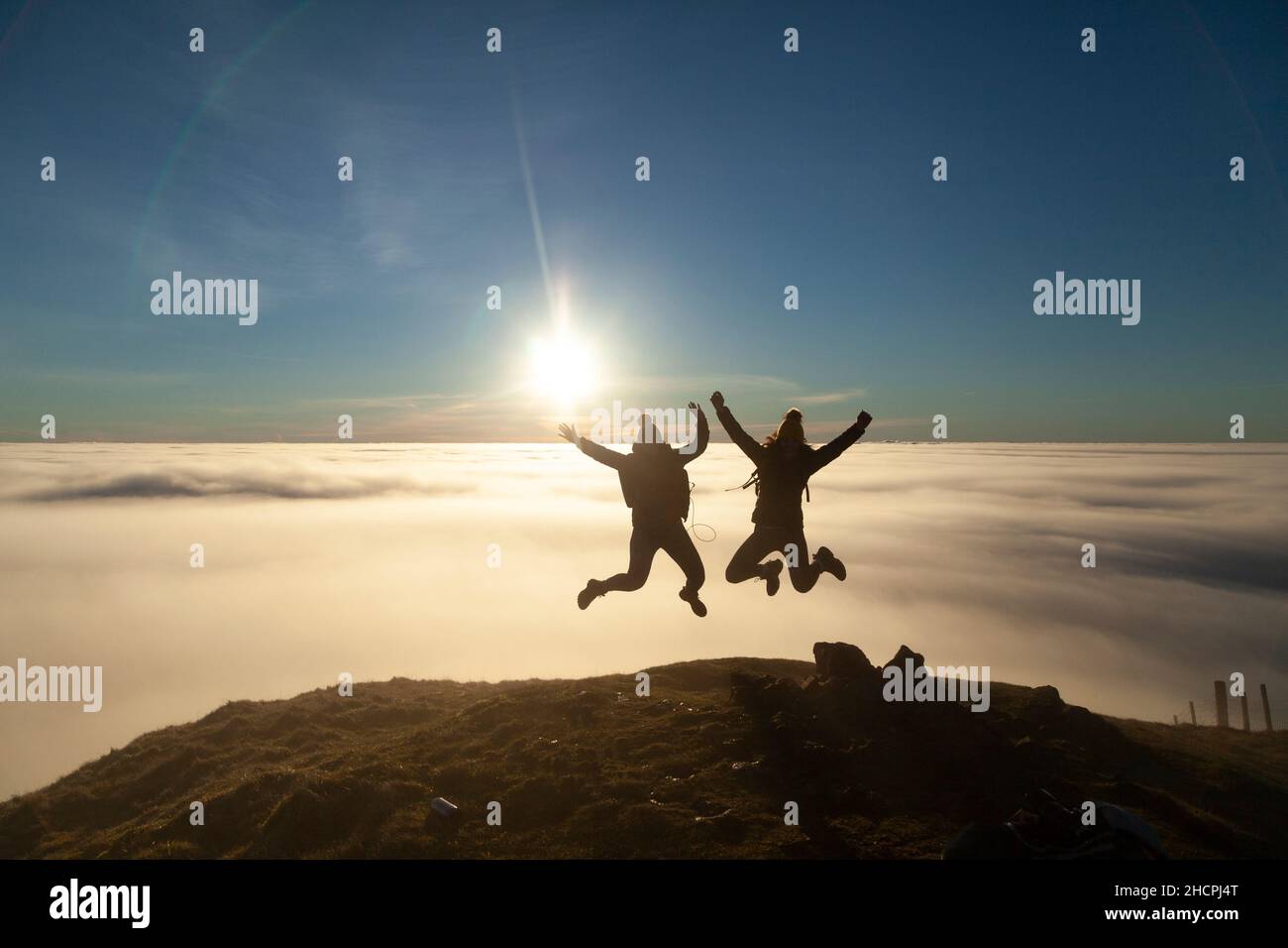 Deux femmes sautant dans l'air avec une mer de nuages derrière elles Banque D'Images