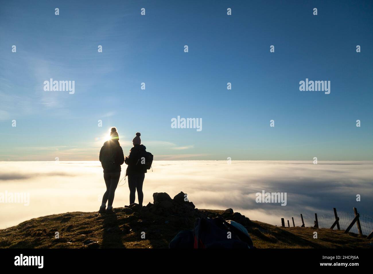 Deux femmes ont silhoueté contre une mer de nuages au sommet d'une colline. Banque D'Images
