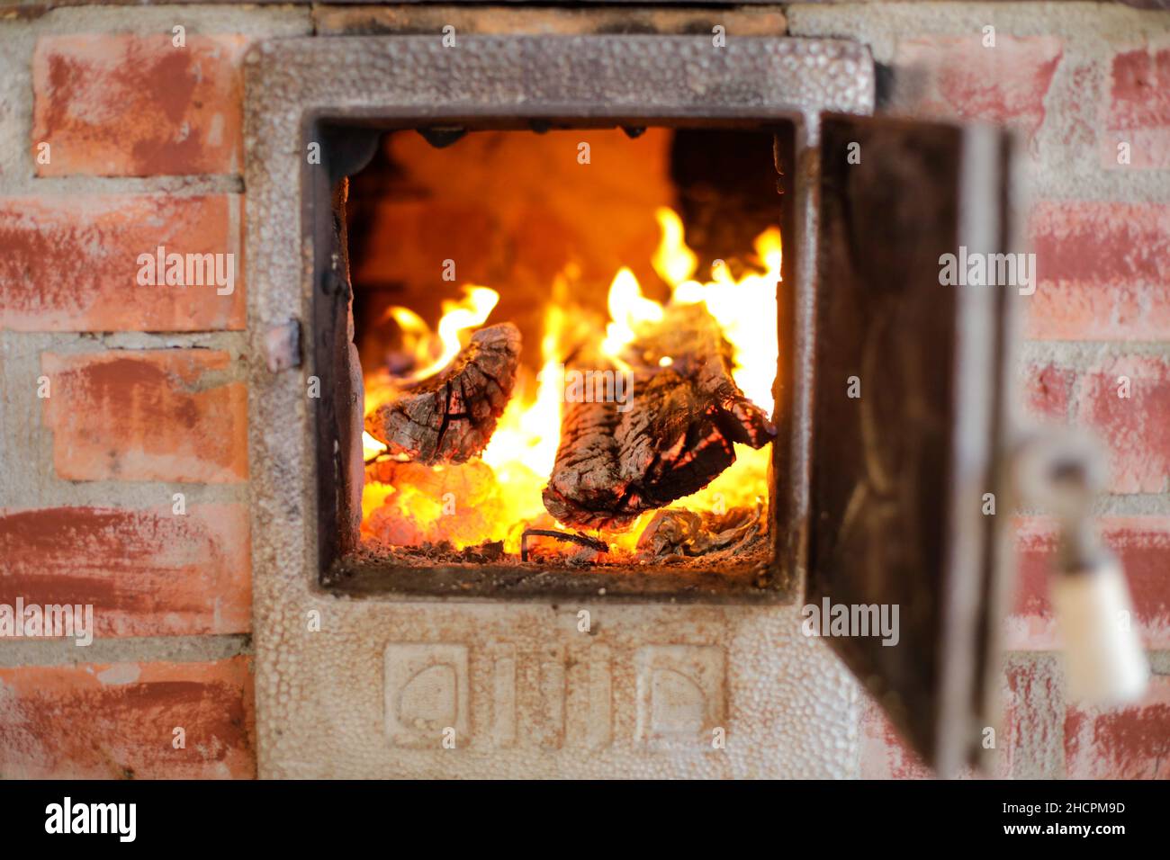 Détails avec feu de bois brûlant à l'intérieur d'un poêle en fer dans l'arrière-cour d'une maison rurale en Roumanie. Banque D'Images
