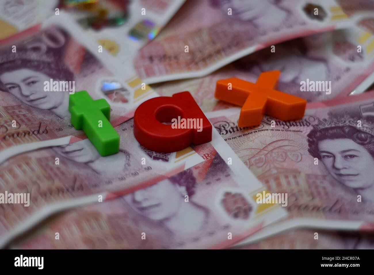 Lettres en plastique avec le mot taxe, taxes, concept de paiement, sur un lit de cinquante billets de £50 livres sterling Banque D'Images