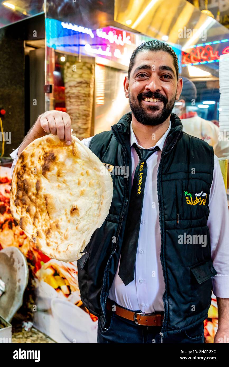 Un ouvrier de restaurant tenant Une pièce de pain plat arabe traditionnel, Amman, Jordanie. Banque D'Images
