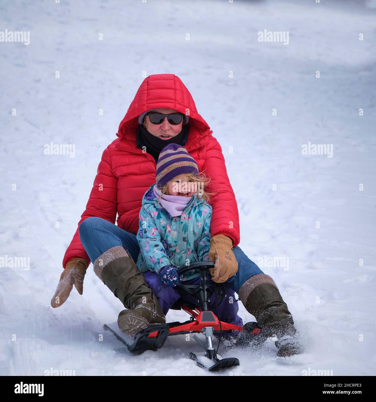 Une fille de 3 ans et sa grand-mère ont traîneaux sur une colline enneigée sur un coureur de neige Banque D'Images