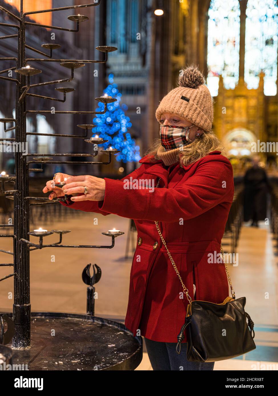 Woman Lights prière Candle à la cathédrale anglicane - Liverpool à Noël Banque D'Images