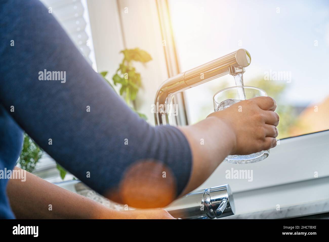 femme tenant le verre au robinet d'eau et remplissant l'eau Banque D'Images