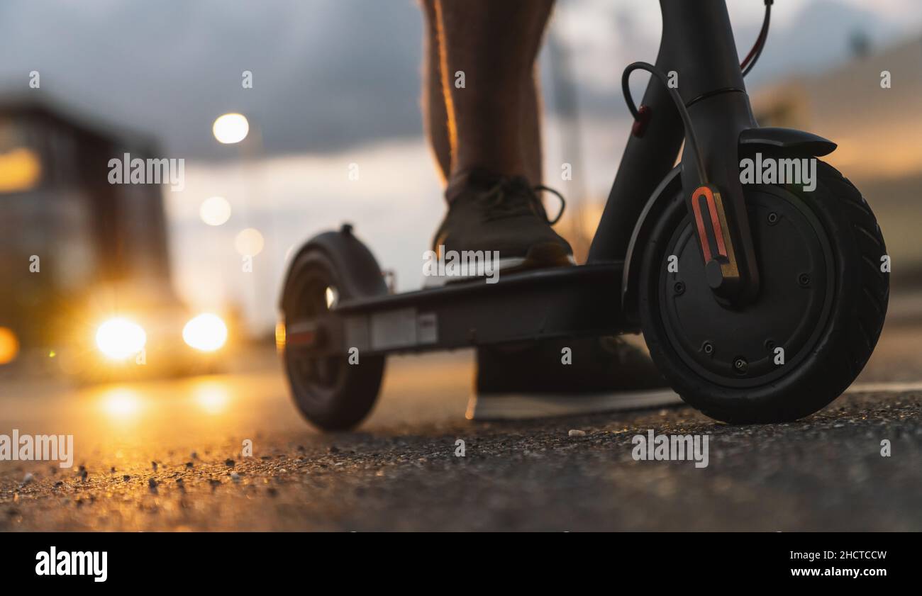 Jeune homme de nuit avec scooter électrique ou e-scooter dans la ville, image concept de transport urbain électrique Banque D'Images