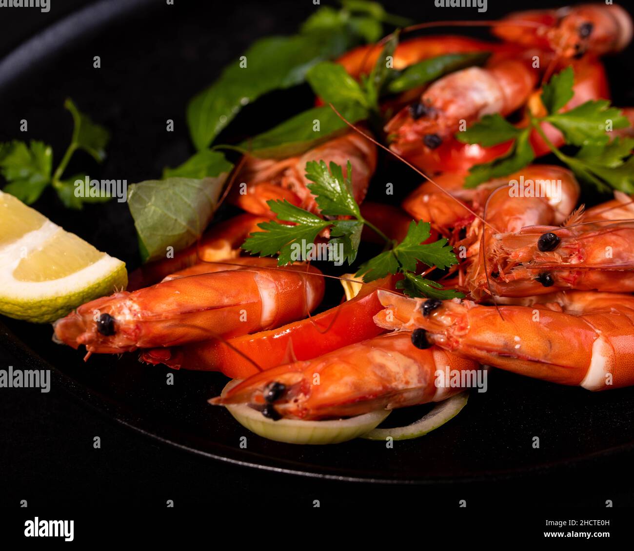 Une assiette de grosses crevettes servies avec des feuilles de citron et de persil frais Banque D'Images