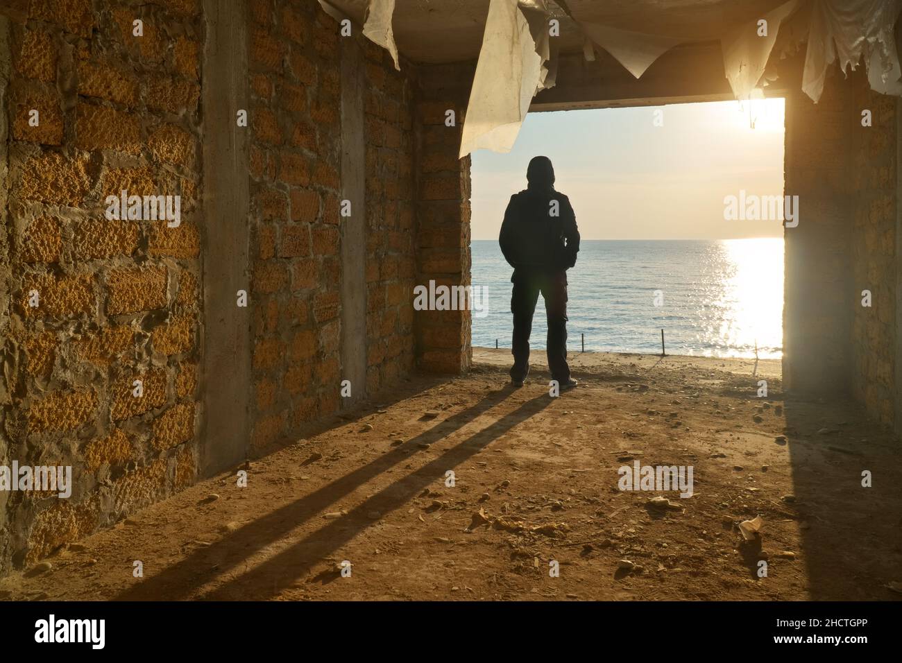 Silhouette d'homme libre.Bâtiment brisé et coucher de soleil sur la mer.Echappée de prison.Composition conceptuelle de la scène. Banque D'Images