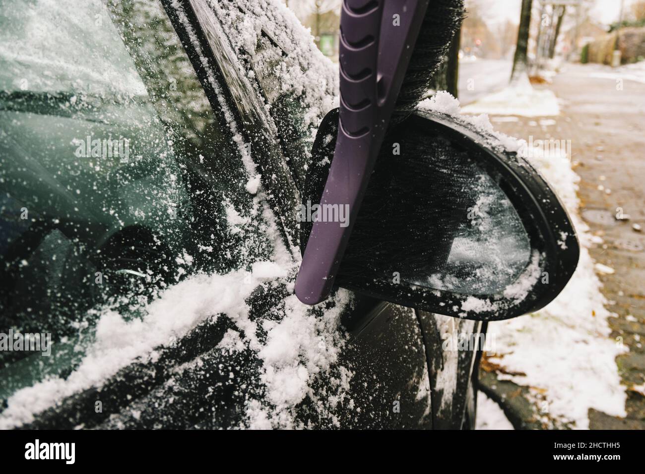 Retirer la neige du rétroviseur latéral d'une voiture à l'aide d'une brosse Banque D'Images