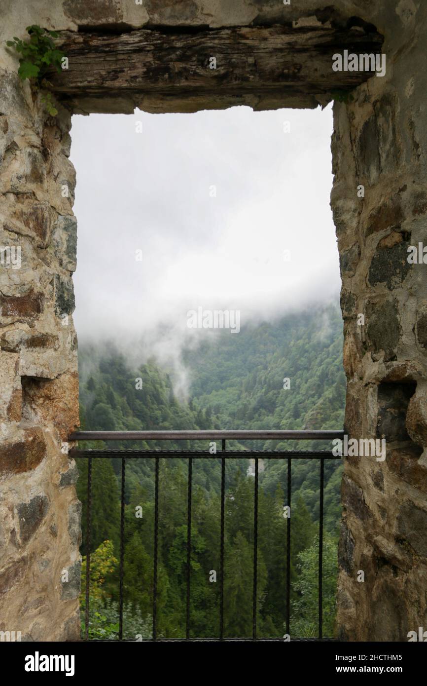 Montagnes brumeuses, montagnes brumeuses et vue sur la forêt depuis une fenêtre en pierre.Mise au point sélective sur le cadre en pierre.Mystérieux et nuageux.Concept de la nature. Banque D'Images