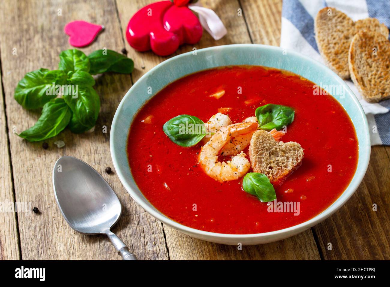 Soupe de Saint-Valentin maison, repas de fête.Soupe de tomates, purée de gazpacho avec tomates, fruits de mer servis sur une table rustique en bois. Banque D'Images