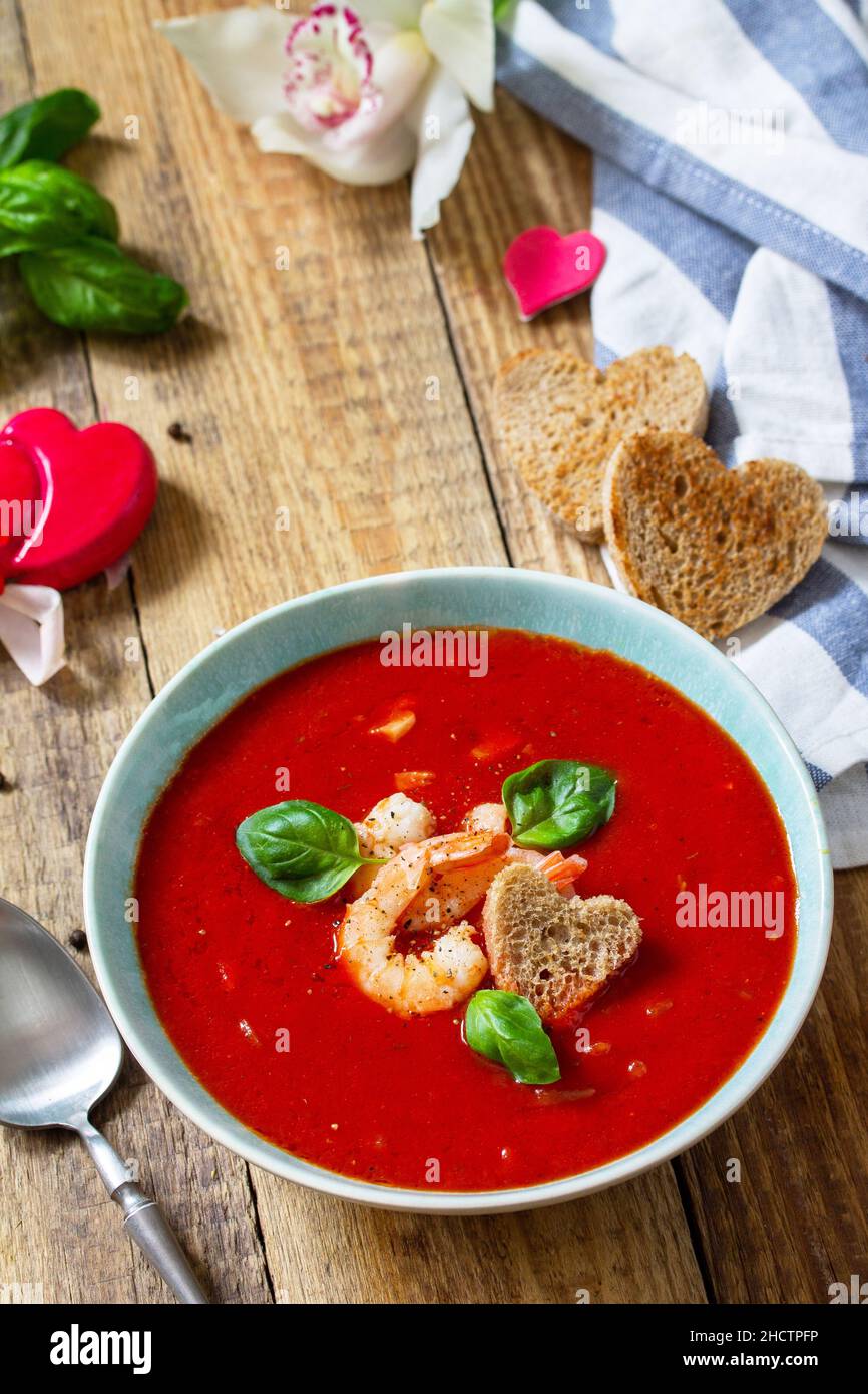 Soupe de Saint-Valentin maison, repas de fête.Soupe de tomates, purée de gazpacho avec tomates, fruits de mer servis sur une table rustique en bois.Copier l'espace. Banque D'Images