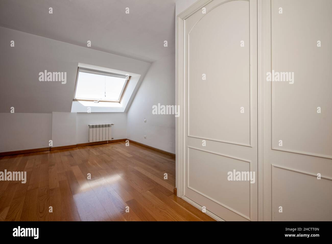 cette chambre vide dispose de plafonds loft, d''une fenêtre et d''une armoire blanche intégrée Banque D'Images