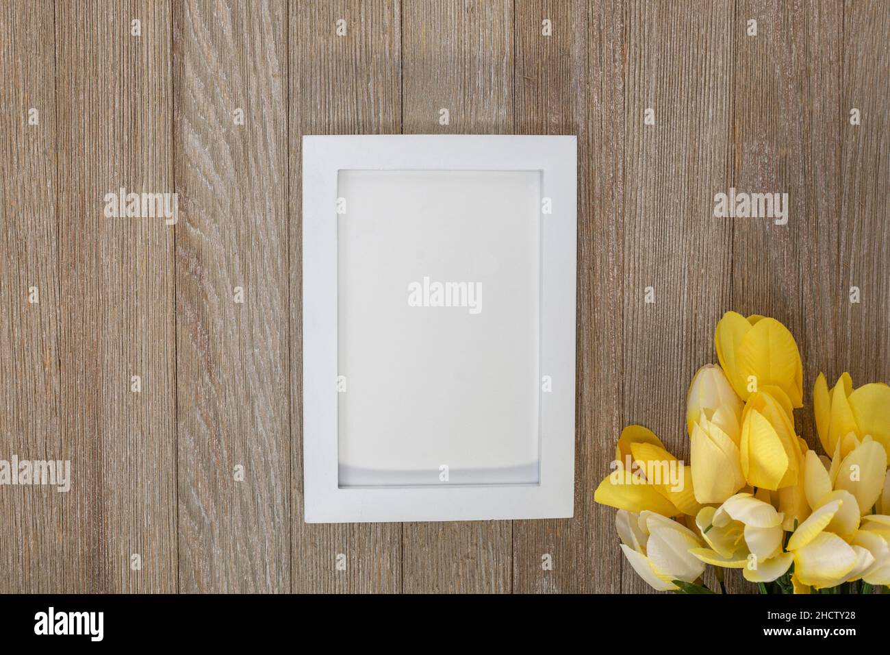 Maquette de cadre blanc sur panneau rustique en bois avec tulipes jaunes plat poser espace de copie Banque D'Images