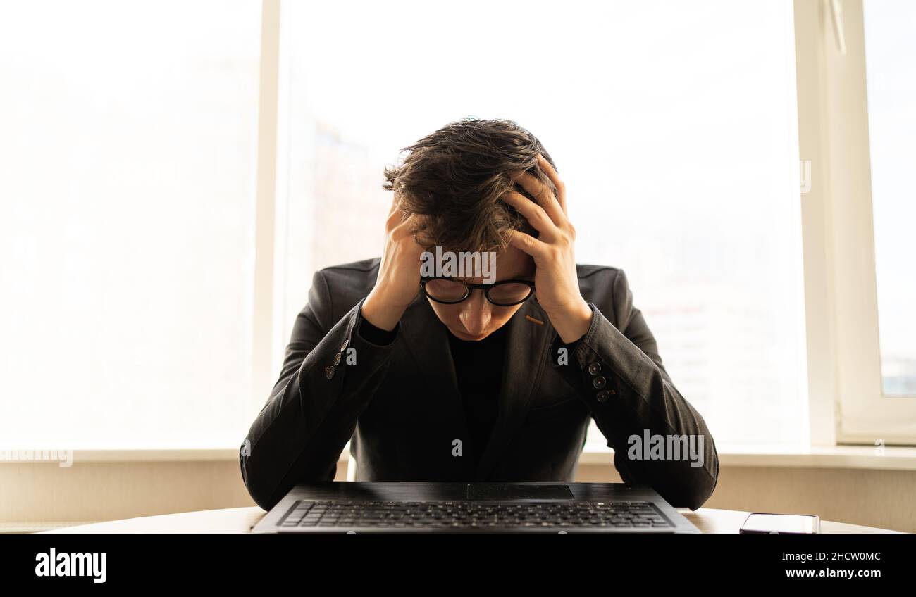 Homme d'affaires déprimé avec mal de tête dans le bureau.Cadre d'affaires avec migraine. Mains sur le chef d'un travailleur indépendant sur le lieu de travail. Banque D'Images