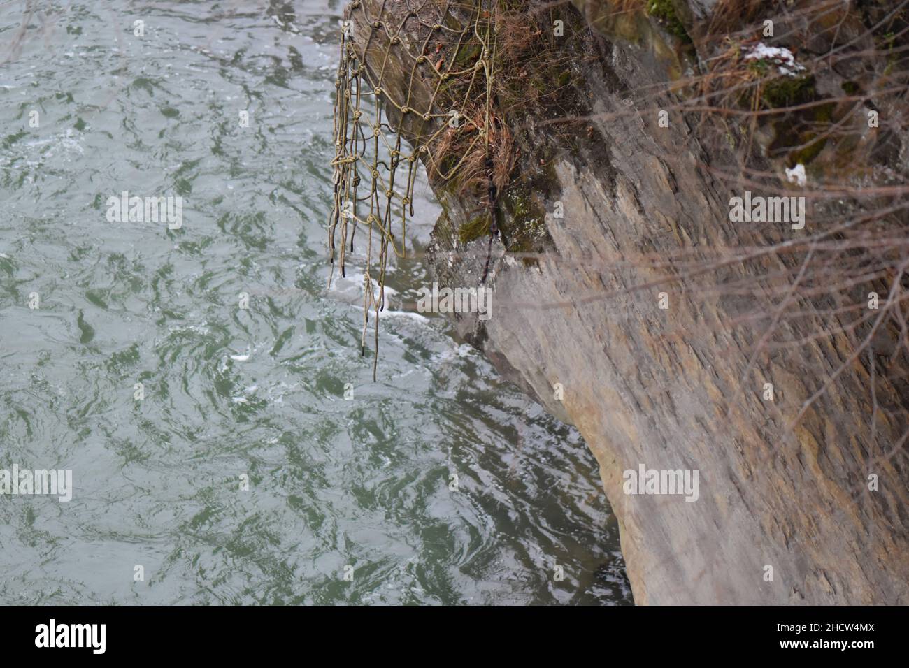 Grenat à angle élevé d'un filet suspendu dans la roche recouverte de mousse au-dessus d'une rivière Banque D'Images