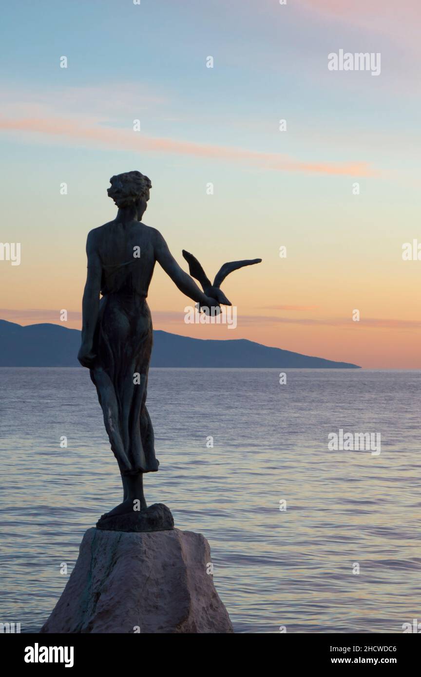 Statue de bronze Maiden avec le mouette, symbole d'Opatija en Croatie, debout sur le récif au bord de la mer Adriatique calme et regardant l'île de Cres Banque D'Images