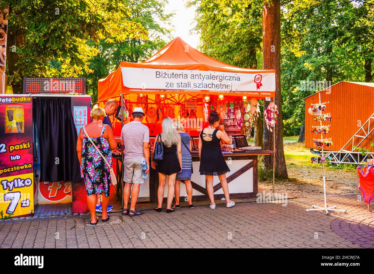 Plusieurs personnes se tenant devant un stand de bijoux lors d'une journée ensoleillée à Ustronie Morskie, Pologne Banque D'Images