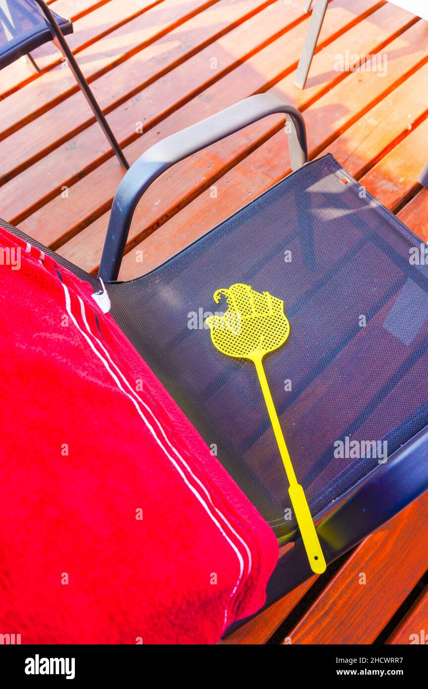 Photo verticale d'une mouche jaune qui se balance sur une chaise par temps ensoleillé avec fond de parquet Banque D'Images