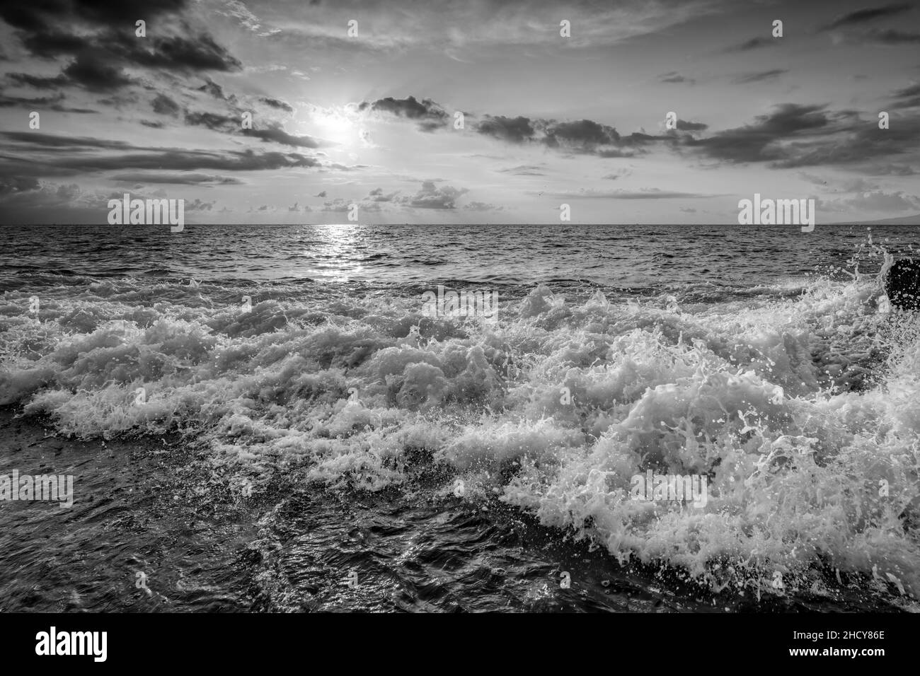 Un ciel de coucher de soleil sur Ocean Seascape avec Un paysage cloudscape détaillé comme Une vague tombe en terre au format d'image noir et blanc Banque D'Images