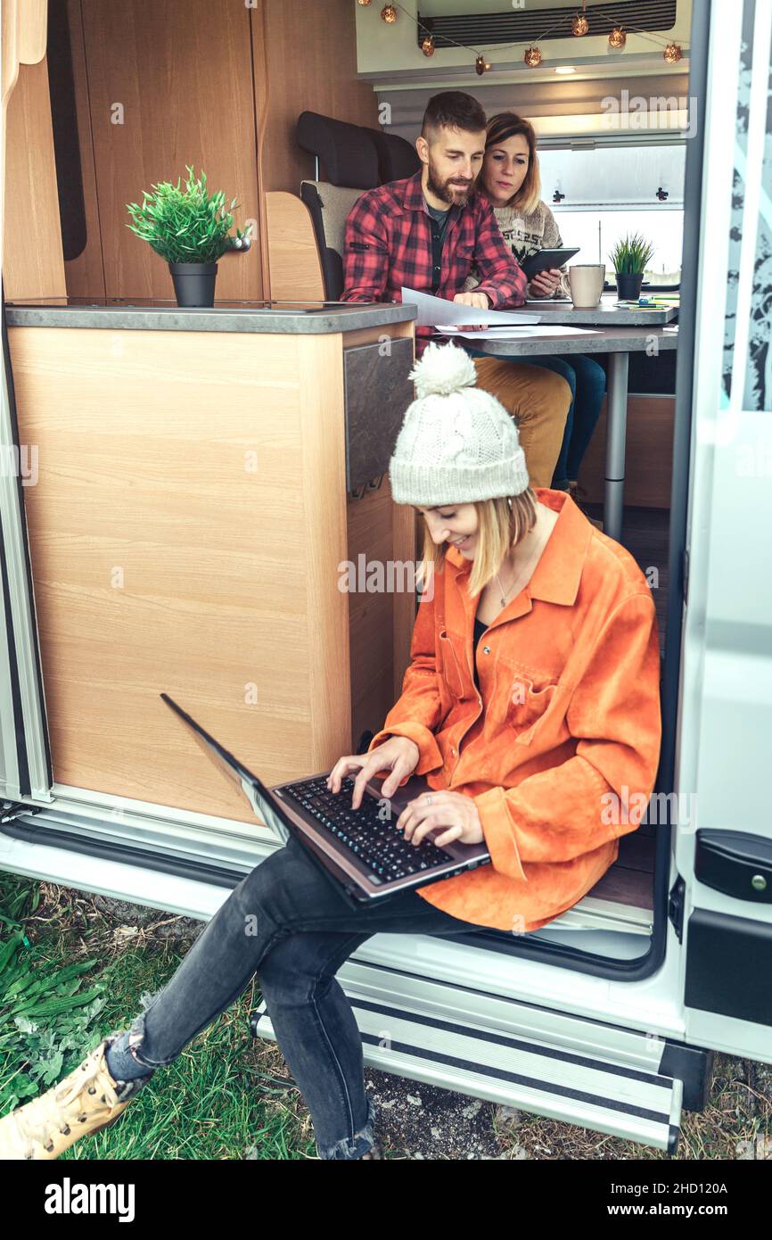 Femme de télétravail assise à la porte d'une camionnette de camping Banque D'Images