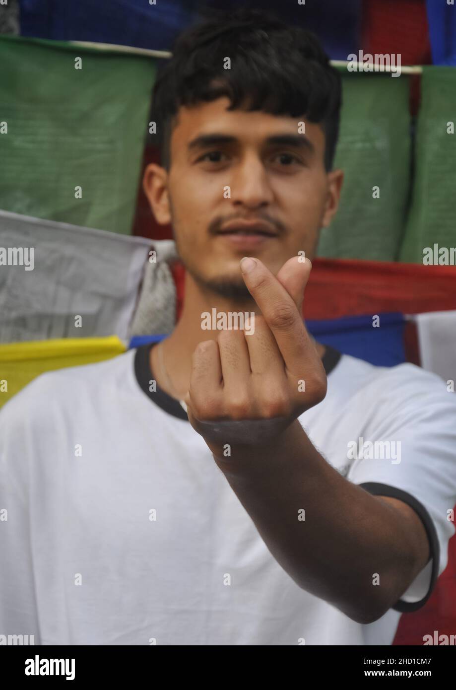 Foyer sélectif d'un jeune homme faisant le signe d'amour coréen avec sa main en regardant la caméra Banque D'Images