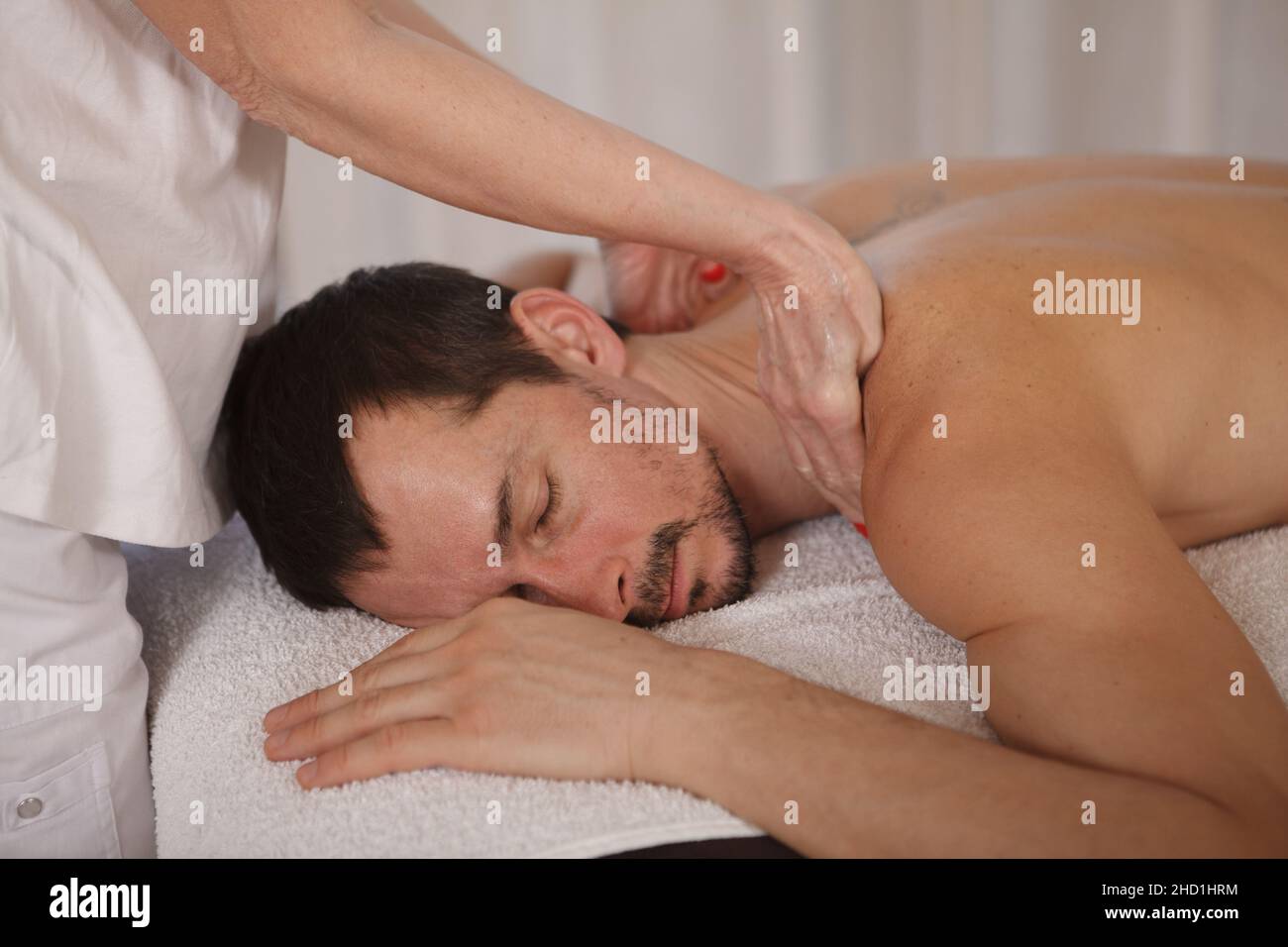 Gros plan sur un homme mature qui se détend au spa et qui se fait masser des tissus profonds par un professionnel Banque D'Images