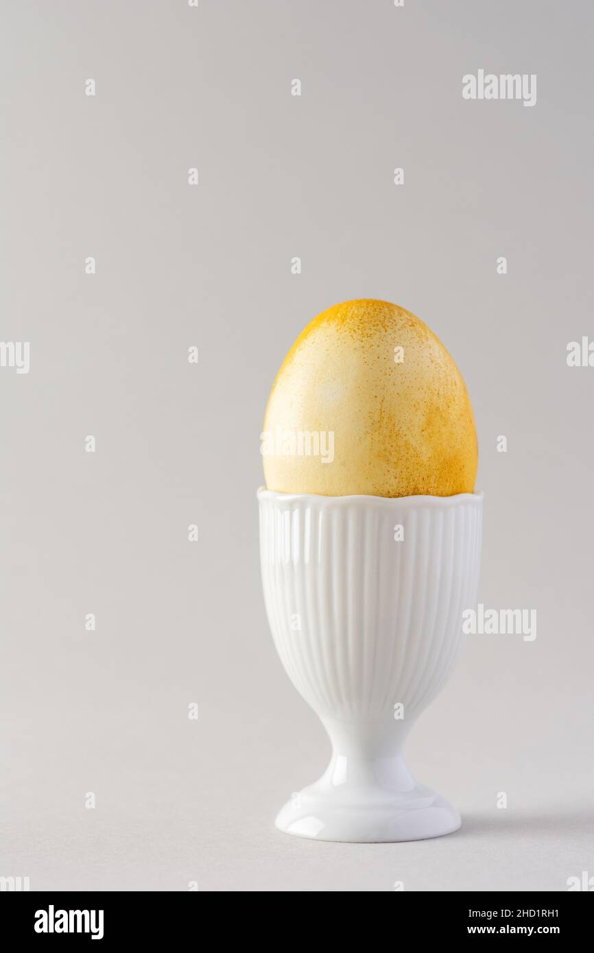 Pâques peint jaune oeuf en blanc forme spéciale pour les oeufs sur fond gris, concept de Pâques Banque D'Images