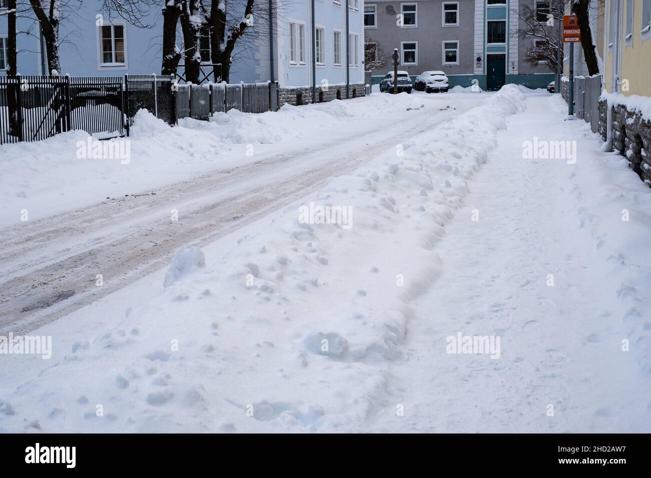 Chaussée enneigée glissante de la ville en hiver.Conditions météorologiques difficiles.Rue et trottoir sous des amas de neige.Circulation dangereuse. Banque D'Images