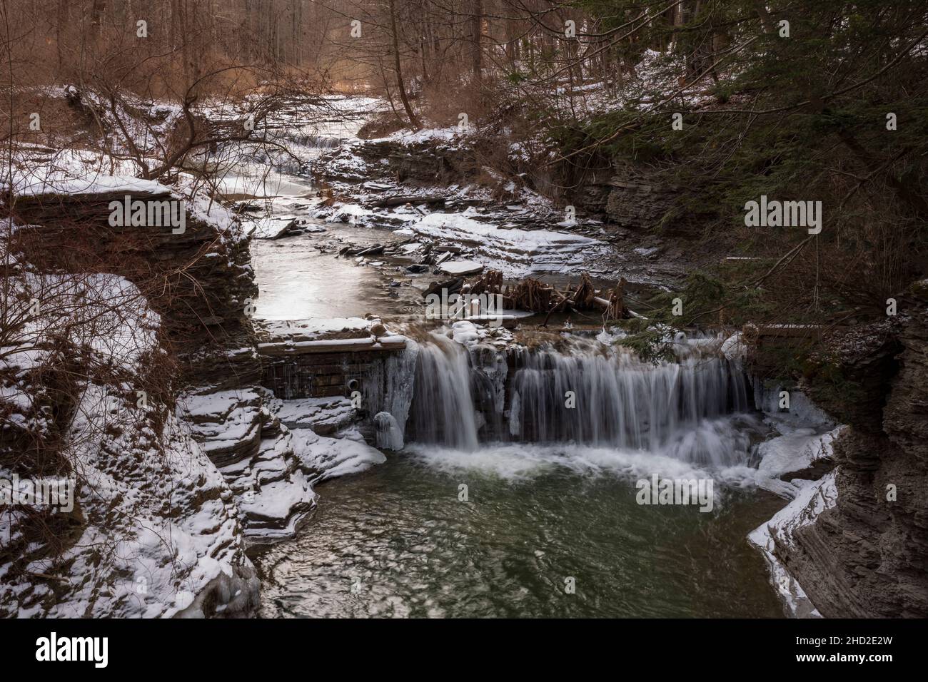 L'eau d'un ruisseau descend en cascade sur une petite cascade au parc national de Buttermilk Falls à Ithaca, NY pendant une journée froide d'hiver. Banque D'Images