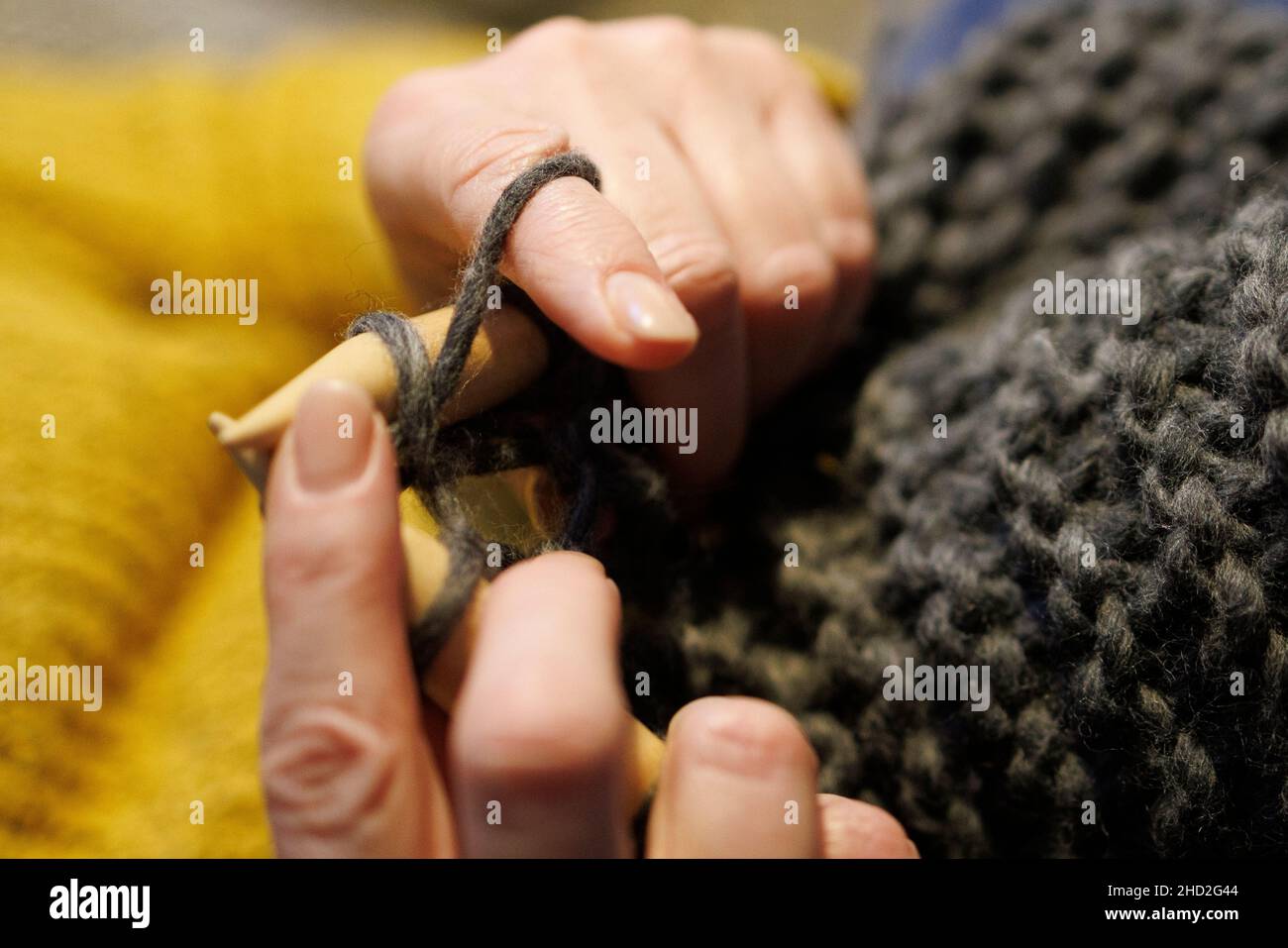 Une femme triait un pull avec des aiguilles à tricoter et de la laine Banque D'Images