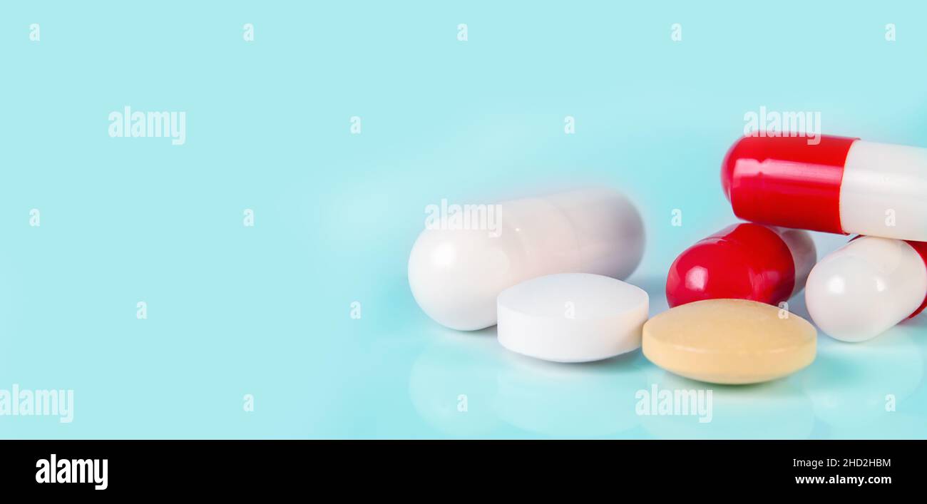 différents types de pilules, de comprimés et de capsules sur fond bleu clair avec réflexion de près Banque D'Images