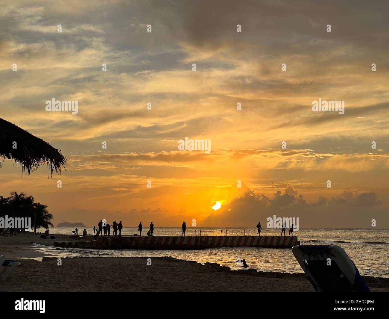 Silhouettes de personnes regardant le coucher du soleil sur Cozumel, Mexique.Grand bateau de croisière nageant sur l'océan pendant le coucher du soleil. Banque D'Images