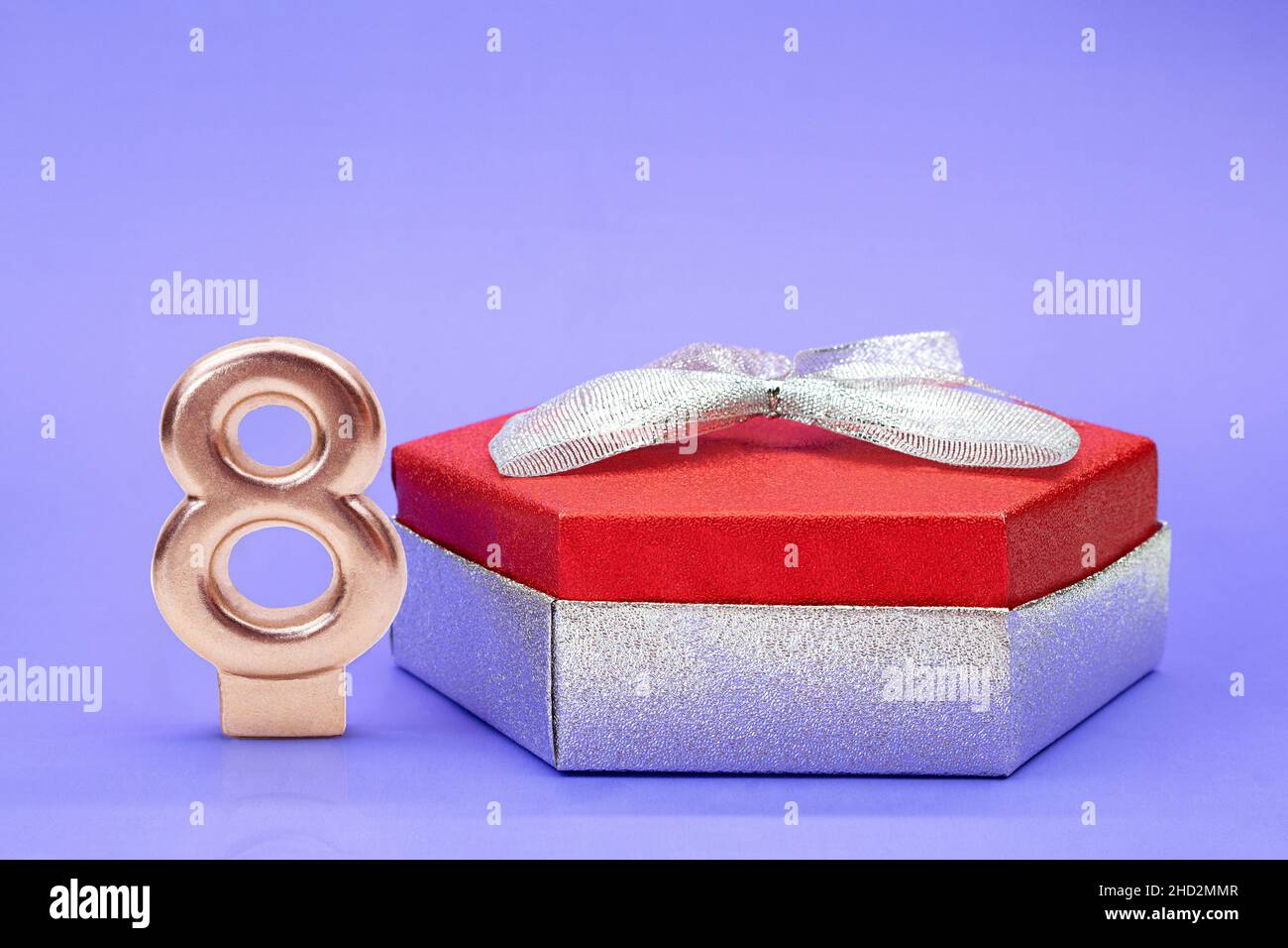 Boîte brillante rouge argent avec noeud et numéro 8 sur fond lilas.Journée internationale de la femme, 8 mars, anniversaire.Copier l'espace Banque D'Images