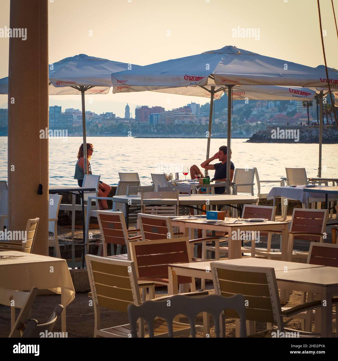 Malaga, Andalousie, Espagne.Juin 2021.Couple assis à la table d'un restaurant au bord de la mer au coucher du soleil. Banque D'Images