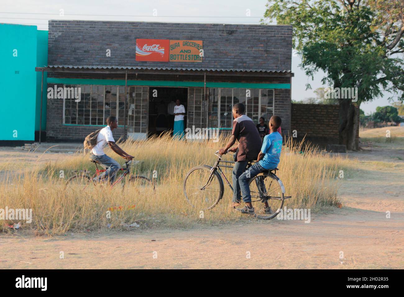 Les jeunes garçons se portent les uns les autres sur des vélos des magasins à un point de croissance Selous, Cheugutu.Le vélo est populaire dans la région.Zimbabwe. Banque D'Images