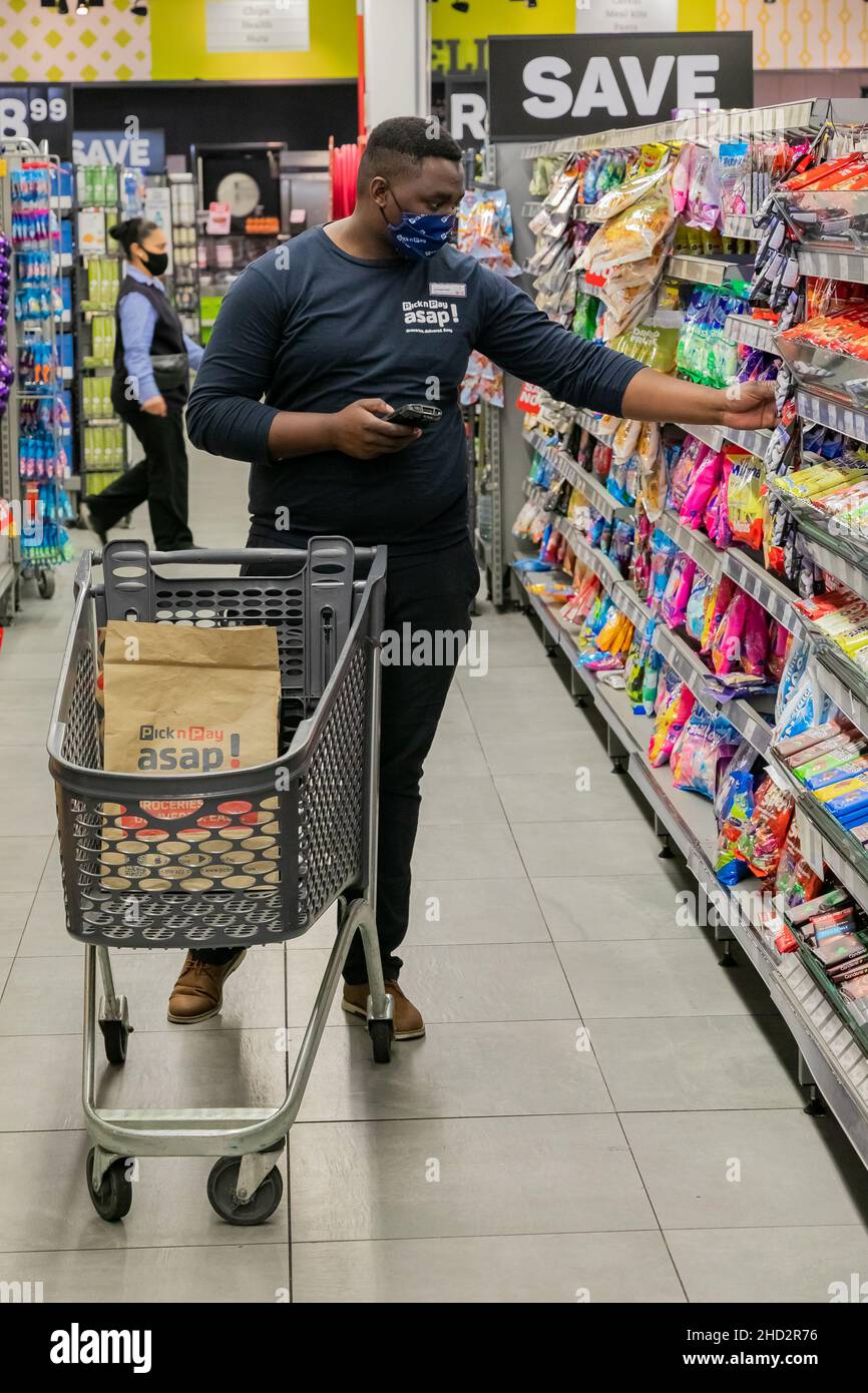 Cape Town, Afrique du Sud - 9 septembre 2021 : un membre du personnel cueille des produits à partir de l'étagère pour un service de livraison express à domicile Banque D'Images