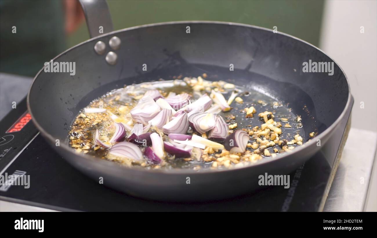 Cuisson des légumes au wok.Attache.Chef friture de l'oignon blanc haché.Hachée dans une poêle.Cuisson à la vapeur à partir de la poêle avec l'oignon.Légumes Banque D'Images