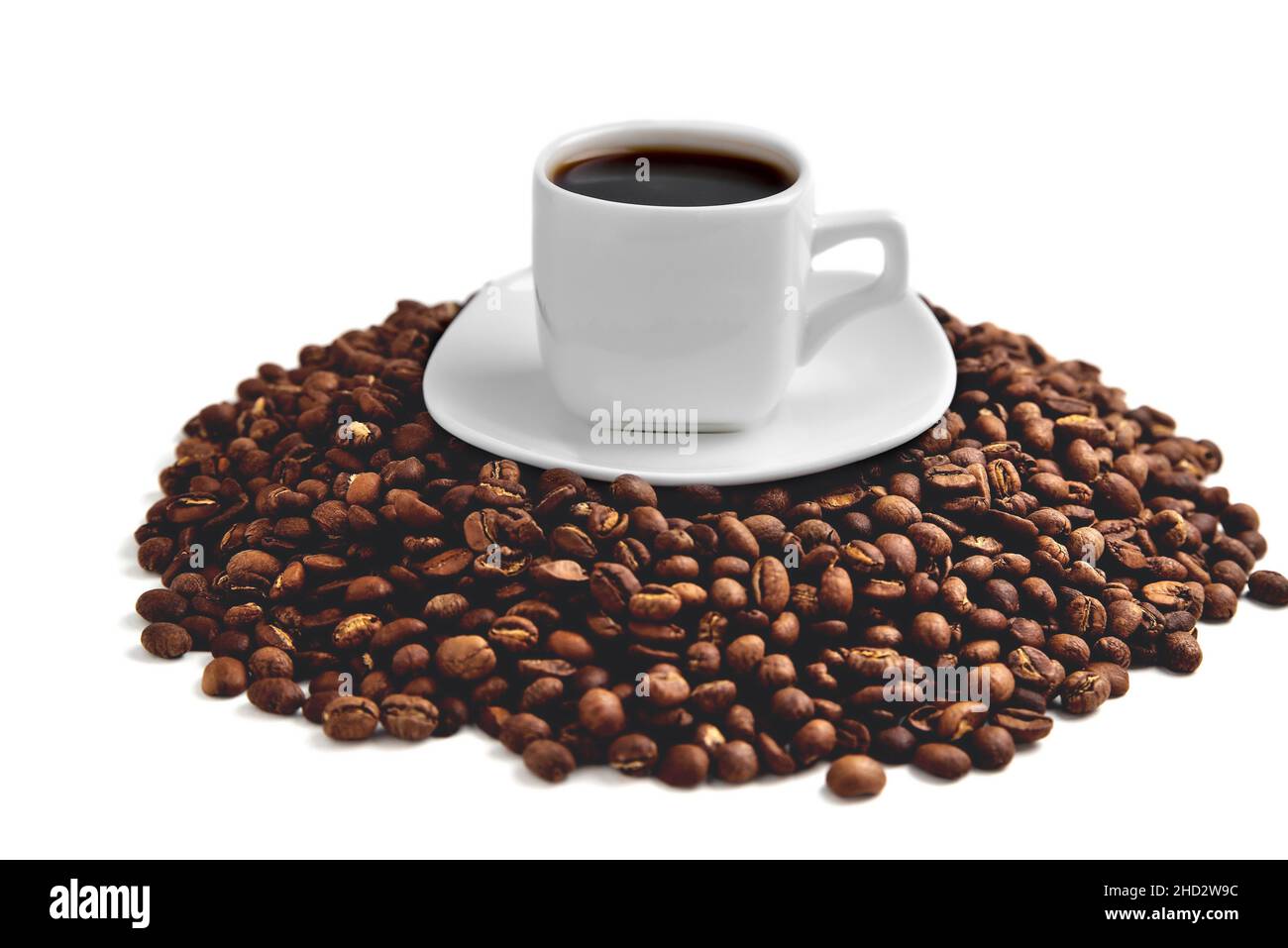 une tasse de café blanc sur une soucoupe blanche se tient sur une colline de grains de café sur un fond blanc isoler, gros plan, vue d'angle du dessus, mise au point sélective Banque D'Images