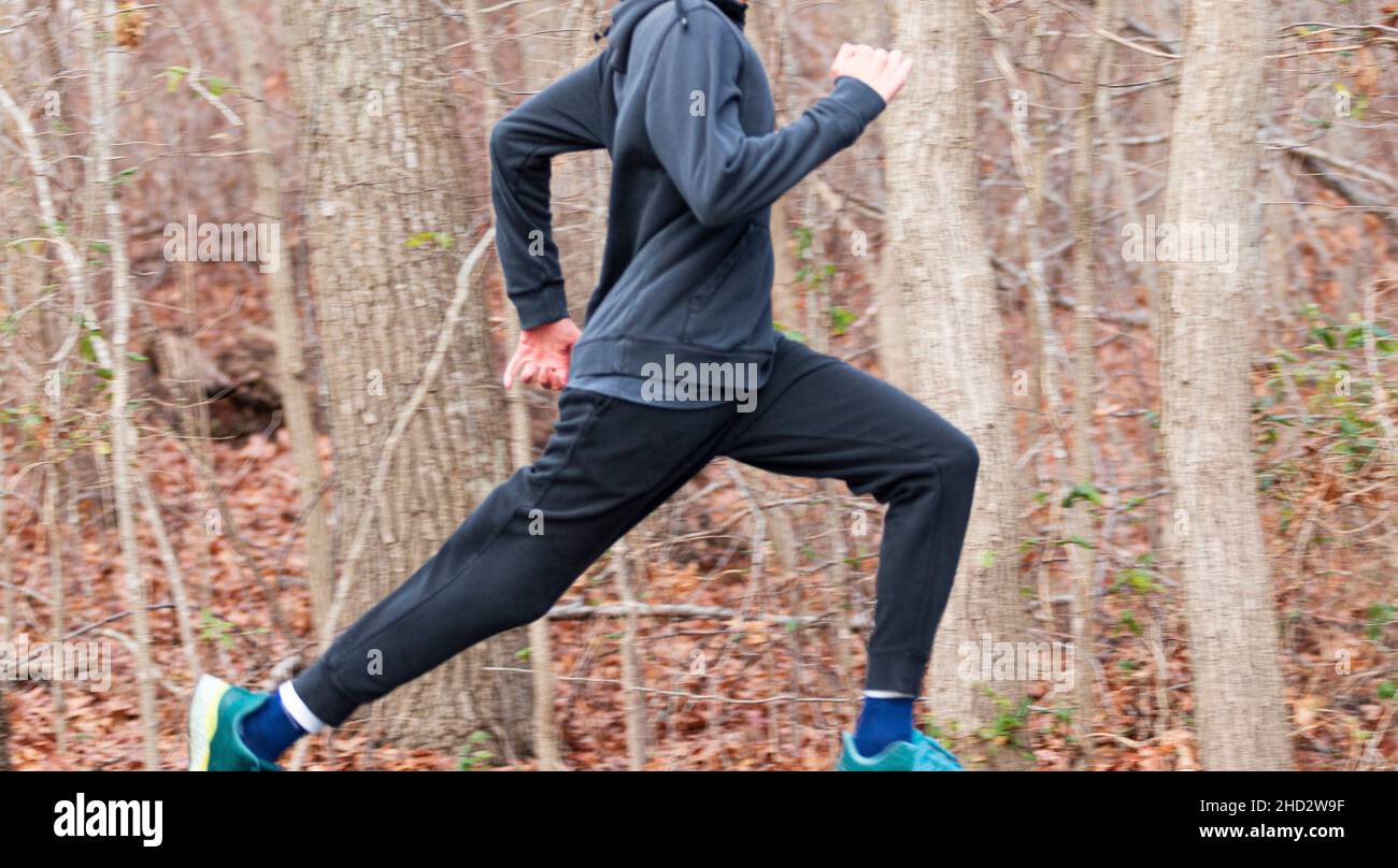 Mise au point sélective sur un coureur rapide qui court sur un chemin dans les bois avec un arrière-plan flou. Banque D'Images