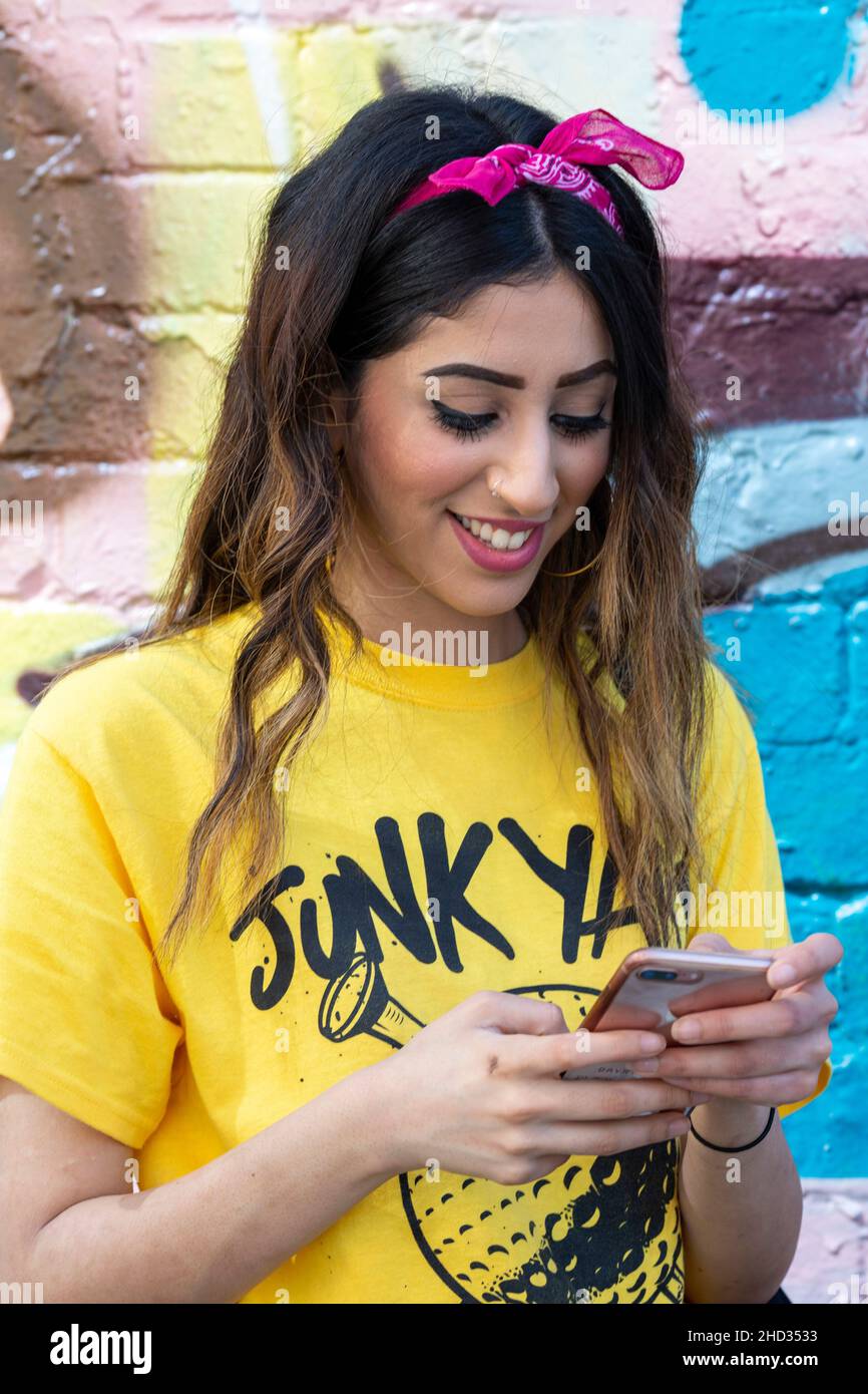 Portrait de mode de rue de la jeune femme regardant son smartphone dans le quartier de la mode cool à l'est de Londres Shoreditch , Royaume-Uni Banque D'Images