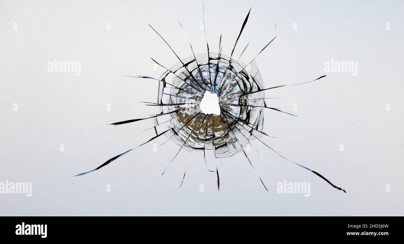 Collage de fissures dans le verre, un trou de balles dans le verre sur un fond blanc. Texture de verre de fenêtre. Banque D'Images