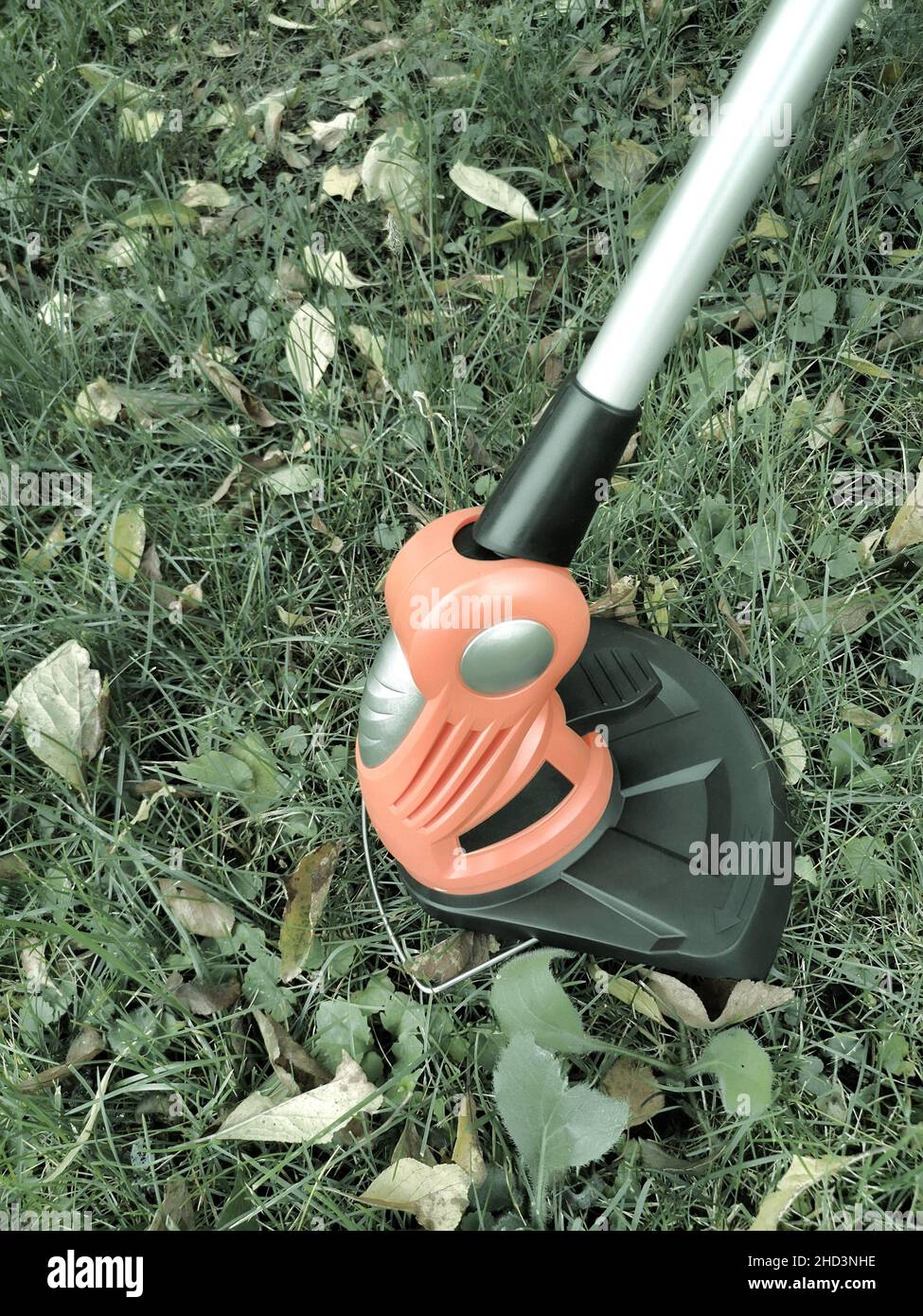 Appareils électroménagers : tondeuse-tondeuse pour couper des pelouses sur des batteries rechargeables.Présenté sur un fond d'herbe et de feuilles, vue avant, Banque D'Images