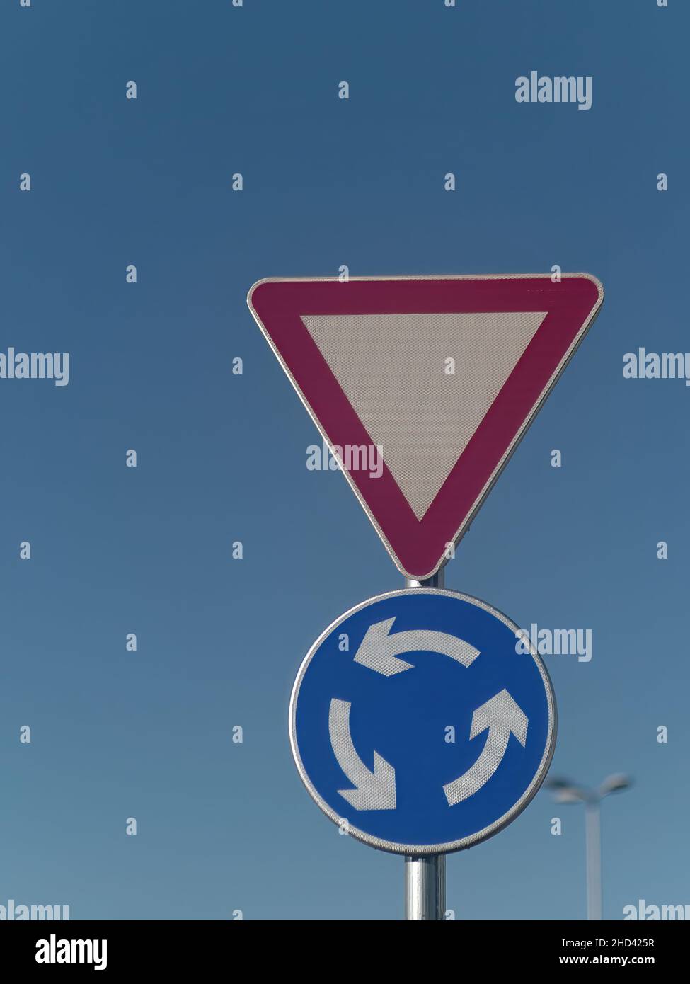 Plan vertical d'un panneau de signalisation de rendement et de rond-point fixé sur un poteau métallique Banque D'Images