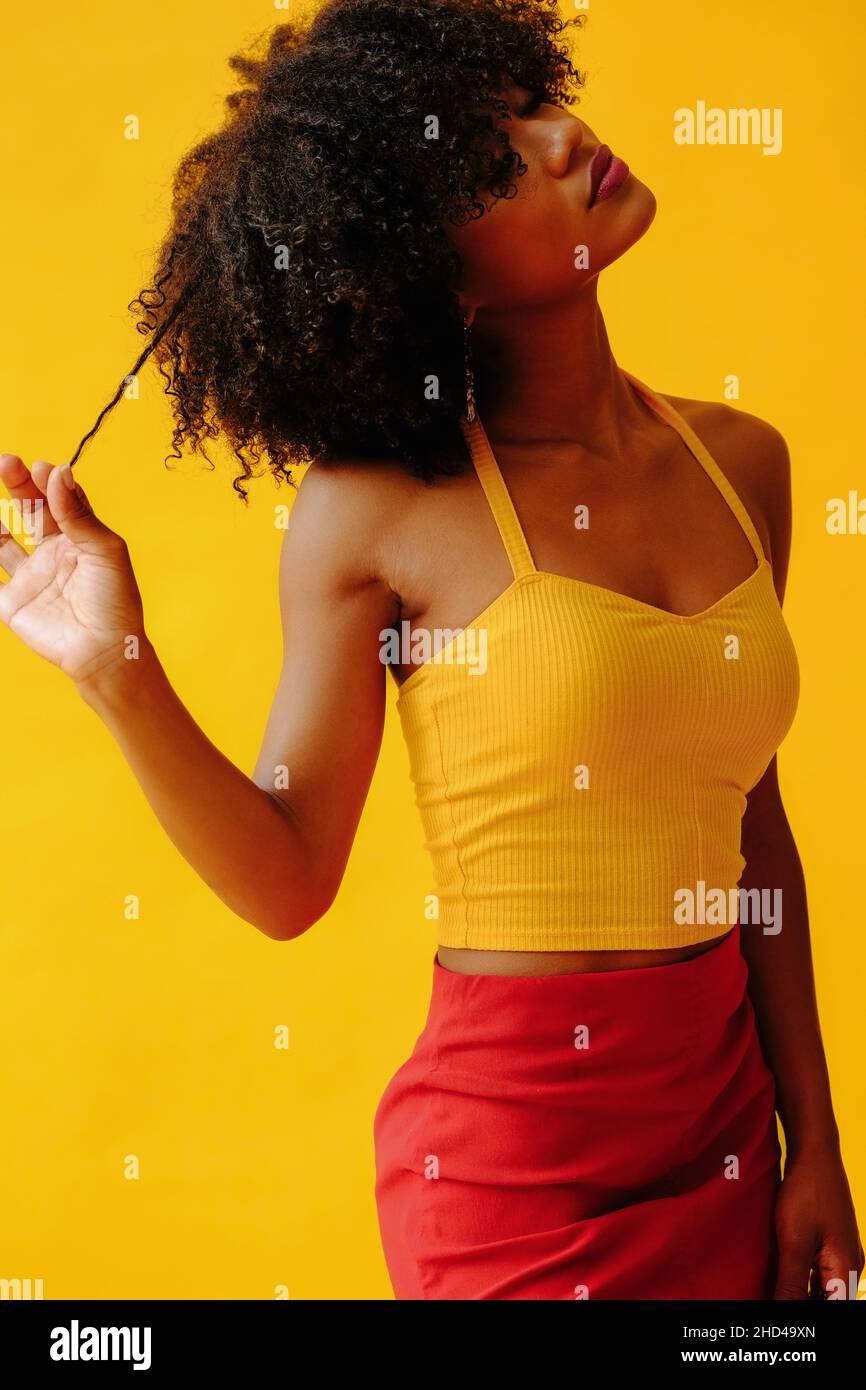 Portrait de la belle jeune femme afro-américaine en tenue d'été lumineuse posant isolée sur fond jaune Banque D'Images