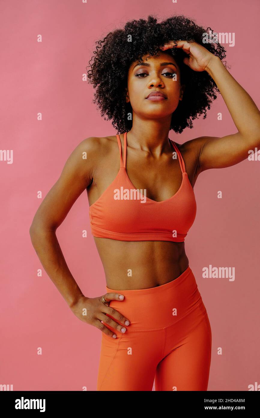 jeune femme en tenue de sport pose isolée sur fond rose Banque D'Images